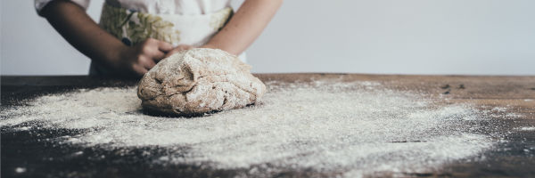 boulanger qui roule le pain dans la farine
