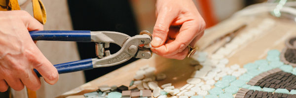 femme qui coupe des morceaux de mosaïque