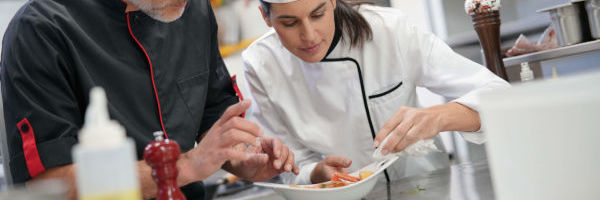 un chef explique un plat à une apprentie