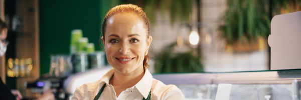 Young female barista standing inside the coffee counter, portrait