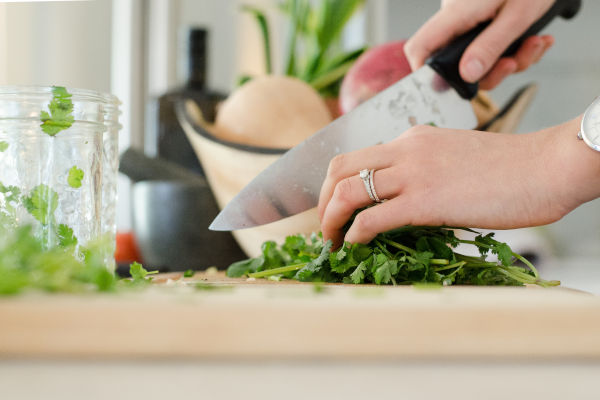 personne qui découpe des légumes sur une planche à découper