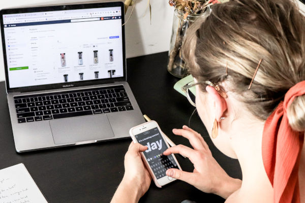 femme sur son téléphone devant son ordinateur