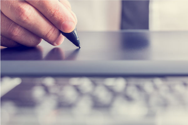 personne qui écrit avec un stylet sur une tablette