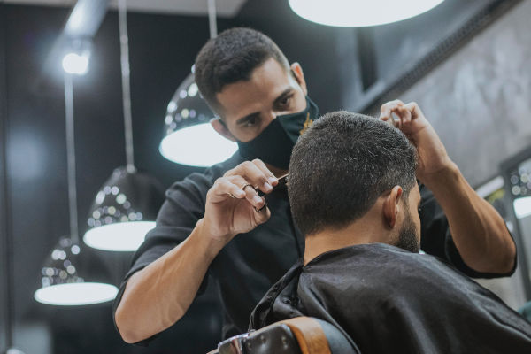 un coiffeur avec un masque qui coiffe un homme