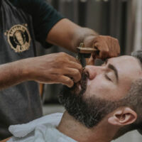 un homme se fait raser chez le barbier