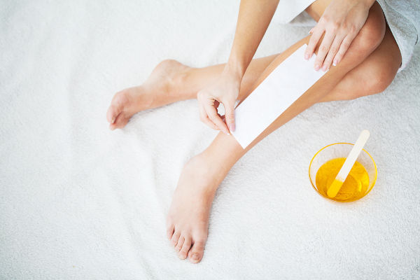 une femme s'épile la jambe à la cire