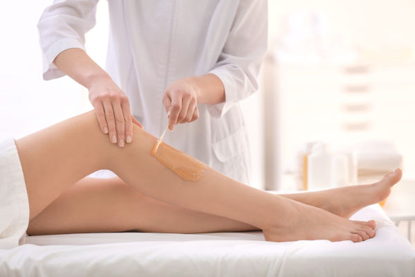 femme qui se fait épiler à la cire par une esthéticienne