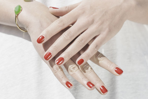 femme avec du vernis à ongle rouge