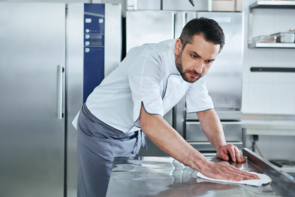 homme qui nettoie une cuisine professionnelle