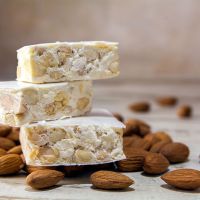 Italian festive torrone or nougat and almonds on a rustic wooden table, copy space, close up with selected focus, very narrow depth of field